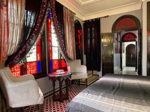 a bedroom with a bed and two chairs and windows at Riad Ibn Battouta & Spa in Fès
