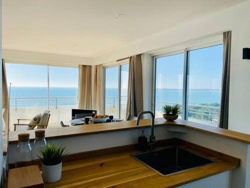 une cuisine avec un évier et un comptoir avec des fenêtres dans l'établissement VUE MER L'horizon Baulois, à La Baule
