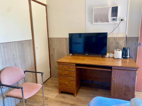 a television on a wooden desk with two chairs at Main Reef Hotel in Boulder
