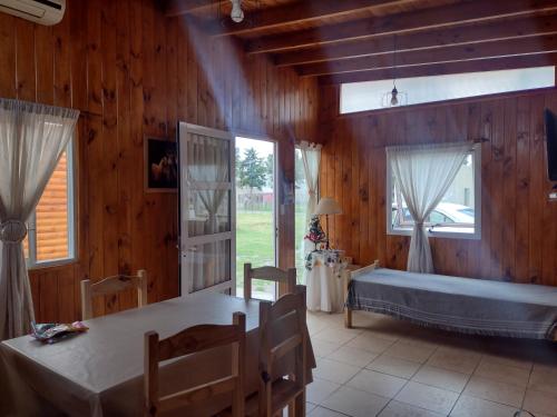Zimmer mit einem Bett, einem Tisch und Fenstern in der Unterkunft Complejo cabañas el paraje in Ranchos