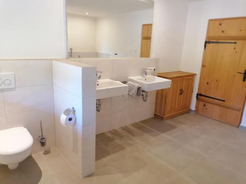 a bathroom with two sinks and a toilet and a mirror at Ferienhaus am Kellpointhof in Miesbach