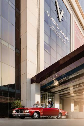 an old red car parked in front of a building at V Hotel Dubai, Curio Collection by Hilton in Dubai