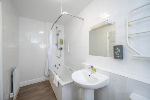 a white bathroom with a sink and a mirror at The Golden Lion Hotel in Hunstanton