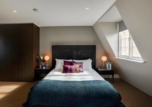 een slaapkamer met een groot bed met paarse kussens bij StayLux Soho in Londen