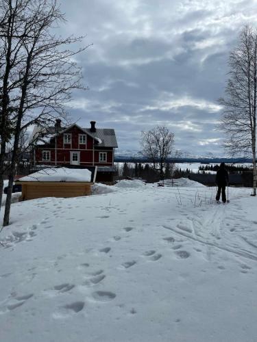 杜威德的住宿－Granlunda Fjällgård，站在房子前的雪中的人