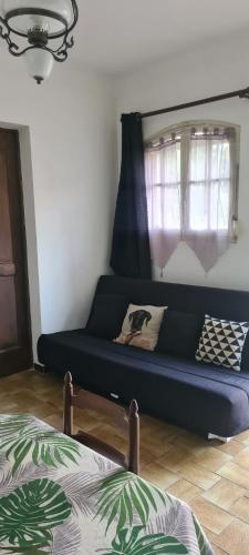 un canapé bleu dans une pièce avec une fenêtre dans l'établissement Entrecasteaux T1 saisonnier, à Entrecasteaux