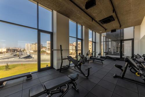 un gimnasio con cintas de correr y elípticas en un edificio con ventanas en Hotel Campus 90 - Free Parking, en Varna