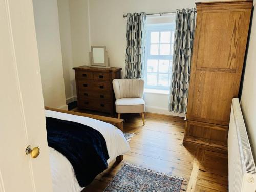 ein Schlafzimmer mit einem Bett und einem Stuhl und einem Fenster in der Unterkunft Lovely Cottage with Mountain Views in Gilwern