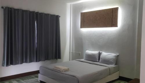 a bedroom with a bed and a window with black curtains at Phontong Garden Resort in Kalasin
