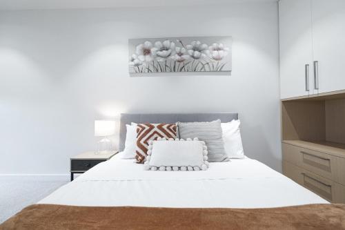 a bedroom with a large white bed with a painting on the wall at Richmond New 1br1ba Free Park Outdoor Bbq in Melbourne