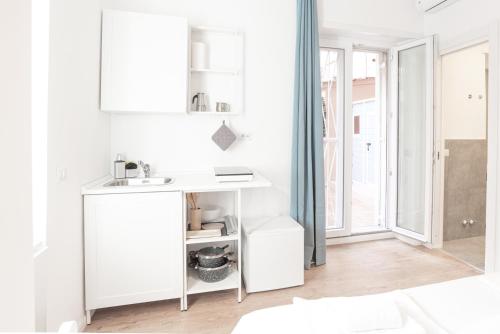 eine weiße Küche mit einem Waschbecken und einem Spiegel in der Unterkunft Residence San Paolo in Rom