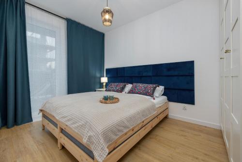 a bedroom with a large bed with a blue headboard at Nadbrzeżna Apartment with Terrace Gąski by Renters in Gąski