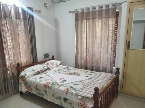 a bedroom with a bed with a floral bedspread at VarkalaEntireHomeKitchenAcRoomsHammocks in Varkala