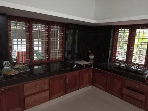 a kitchen with wooden cabinets and black counter tops at VarkalaEntireHomeKitchenAcRoomsHammocks in Varkala