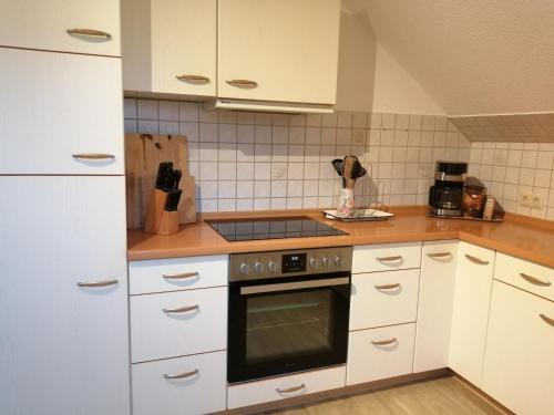 a kitchen with white cabinets and a stove top oven at Dorfidyll im Grünen in Mittelherwigsdorf