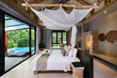 a bedroom with a large bed with a white canopy at Twin Lotus Resort and Spa - SHA Plus - Adult Only Hotel in Ko Lanta