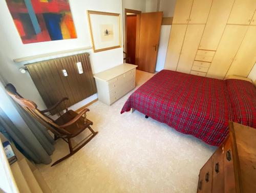 a bedroom with a red bed and a chair at San15 in Predazzo