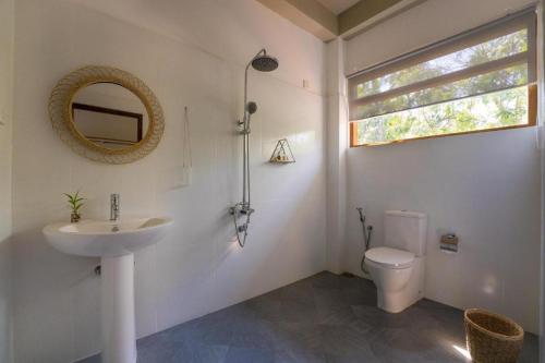ein Badezimmer mit einem Waschbecken, einem WC und einem Spiegel in der Unterkunft Taboo in Hiriketiya
