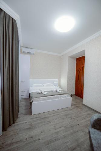 a white bedroom with a bed and a window at Opera Avenue Hotel in Yerevan