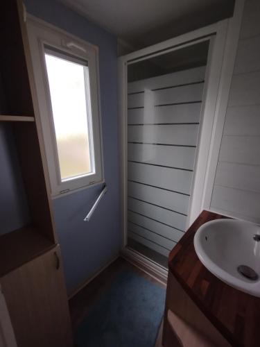une salle de bain avec un lavabo et une fenêtre dans l'établissement Mobil Home cosy 5 personnes proche du Puy Du Fou, à La Boissière-de-Montaigu