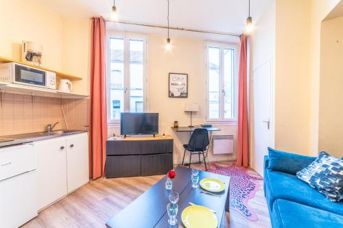 Il comprend un salon avec un canapé bleu et une cuisine. dans l'établissement Le Studio Nérisien - Studio pour 2, à Néris-les-Bains