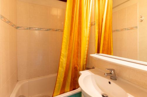 łazienka z pomarańczową zasłoną prysznicową i umywalką w obiekcie Lac et Montagne - Vue sur le lac de Matemale w mieście Les Angles