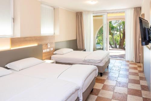 a hotel room with two beds and a television at Residenza Panorama in Costermano