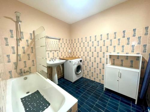 La salle de bains est pourvue d'une baignoire, d'un lavabo et d'un lave-linge. dans l'établissement Vue Port de plaisance : Le Voilier, à La Baule