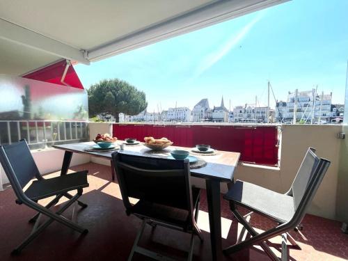 une table et des chaises sur un balcon avec vue sur une ville dans l'établissement Vue Port de plaisance : Le Voilier, à La Baule