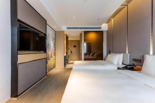 a hotel room with two beds and a flat screen tv at Atour Hotel Shengzhou in Shengzhou