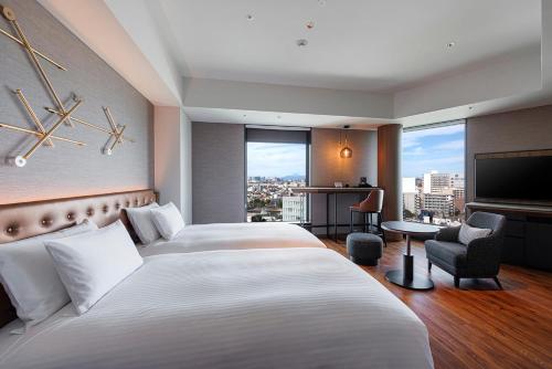 a hotel room with two beds and a flat screen tv at Hotel Metropolitan Tokyo Haneda - 2023-10-17 Grand Opening in Tokyo