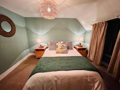 1 dormitorio con 1 cama con pared verde en Honeysuckle cottage, a cosy coastal retreat, en Dornoch