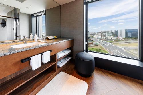 Hotel Metropolitan Tokyo Haneda - 2023-10-17 Grand Opening في طوكيو: حمام مع حوض ونافذة كبيرة