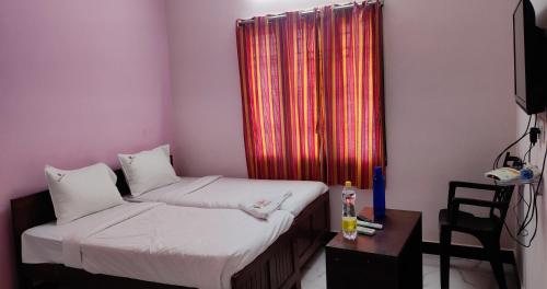 a room with two beds and a television and a window at PPH Living Lakshmi Palace in Tallākulam