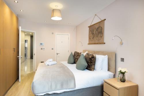 - une chambre avec un grand lit blanc et des oreillers bleus dans l'établissement Luxurious 2 King-size bed flat with Patio, à Londres