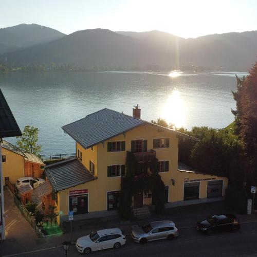 a building with cars parked in front of a lake at Ferienhaus Steinbacher direkt am Tegernsee in Tegernsee