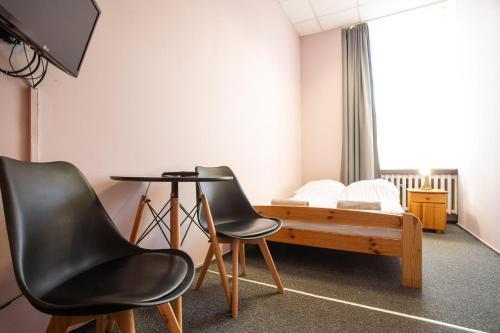 a room with a bed and two chairs and a table at Moon Hostel Wrocław in Wrocław