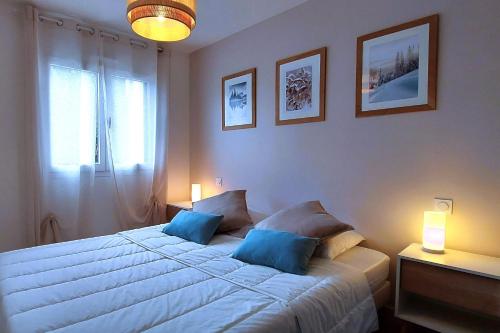 una camera da letto con un grande letto con cuscini blu di Le Cosy Alpin, T2, parking proche lac ad Annecy