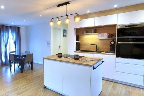 une cuisine avec des armoires blanches et une table et une salle à manger dans l'établissement Le Cosy Alpin, T2, parking proche lac, à Annecy