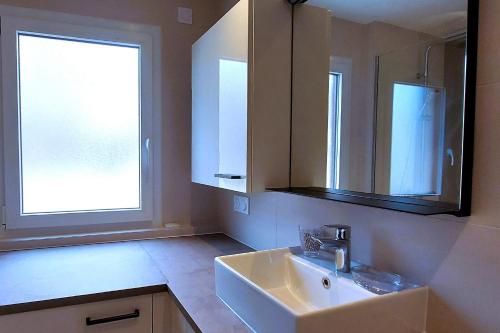 bagno con lavandino, finestra e specchio di Le Cosy Alpin, T2, parking proche lac ad Annecy