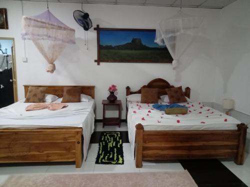 シギリヤにあるsigiriya village hostelのベッドルーム1室(ベッド2台、壁掛けテレビ付)