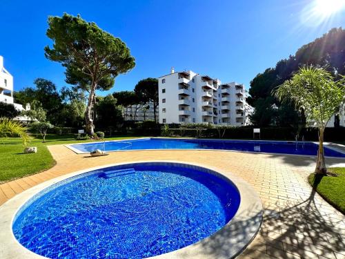 a large blue swimming pool in a park with buildings at Vilamoura - Spacious with Swimming Pool & View in Vilamoura