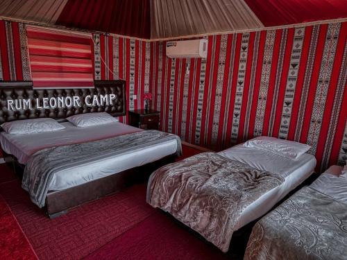 two beds in a room with red and white stripes at RUM LEONOR CAMP in Wadi Rum