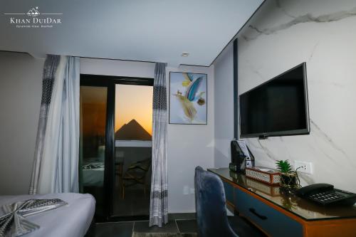 a bedroom with a desk with a television and a bed at Khan Duidar Inn - Pyramids View Rooftop in Cairo