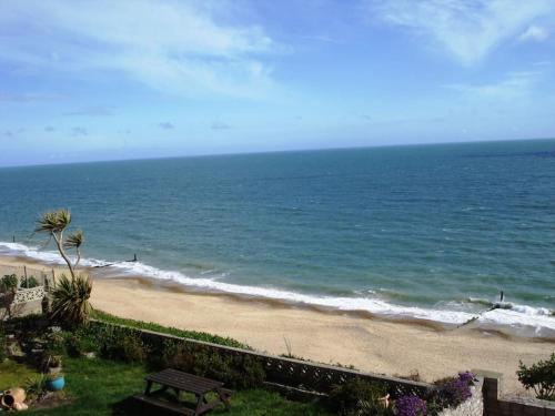 uma vista para uma praia com um banco e para o oceano em BOURNECOAST: BUNGALOW - AMAZING SEA VIEWS - HB2656 em Bournemouth
