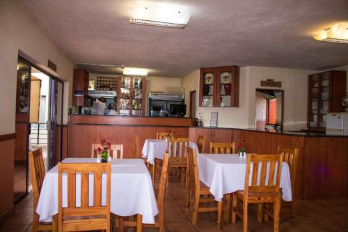 una sala da pranzo con tavoli bianchi e sedie in legno di Pits lodge a Polokwane