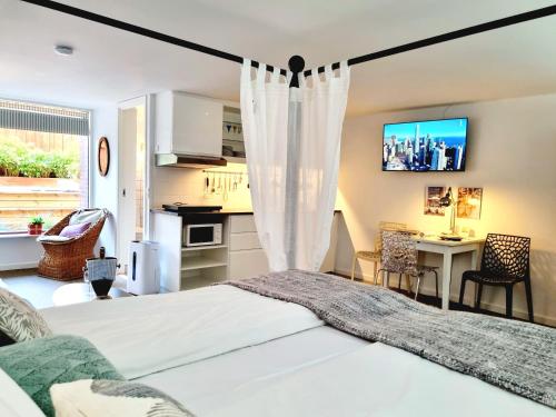 a bedroom with a white bed and a kitchen at Neptun Studio-apartment with terrace. in Copenhagen
