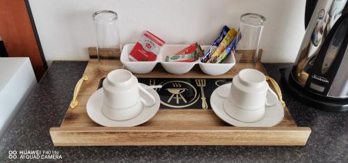 a wooden tray with plates and bowls on a counter at Pits lodge in Polokwane