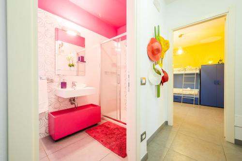 ein rosafarbenes Bad mit einem Waschbecken und einem WC in der Unterkunft 3 MIN DAL MARE - Aria Condizionata - Parcheggio Privato"CASA DEI COLORI" in Lido di Camaiore