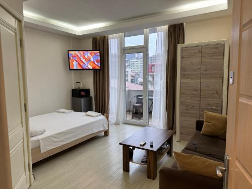 a hotel room with a bed and a couch and a tv at Iko's Family Apartments in Batumi